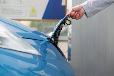 Bir adam elektrik arabasını şarj istasyonunda şarj ediyordu.