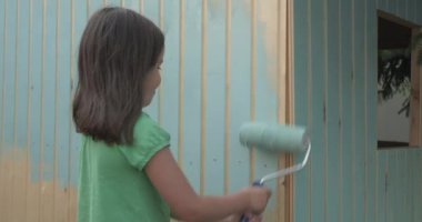 Genç kız bir rulo ile küçük ahşap ev boyama