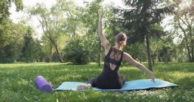 Yeşil parkta pilates yapan güzel bir kadın.