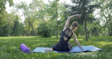 Yeşil parkta pilates yapan güzel bir kadın.