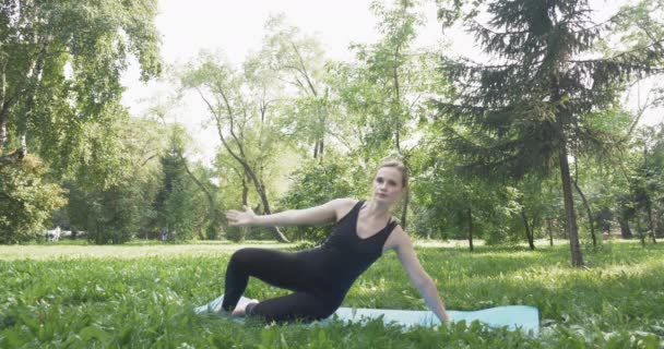 Vacker kvinna gör pilates i den gröna parken — Stockvideo