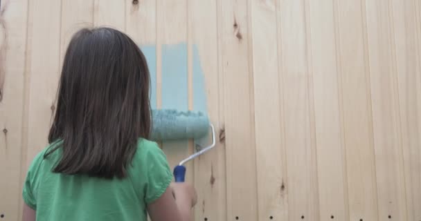 Niña pintando casita de madera con un rodillo — Vídeos de Stock