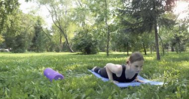 Yeşil parkta pilates yapan güzel bir kadın.