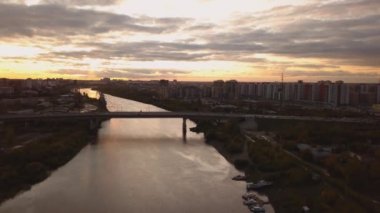 Dramatik renkli gün batımında bir nehir ve üzerinde bir köprü havadan panoramik görünümü