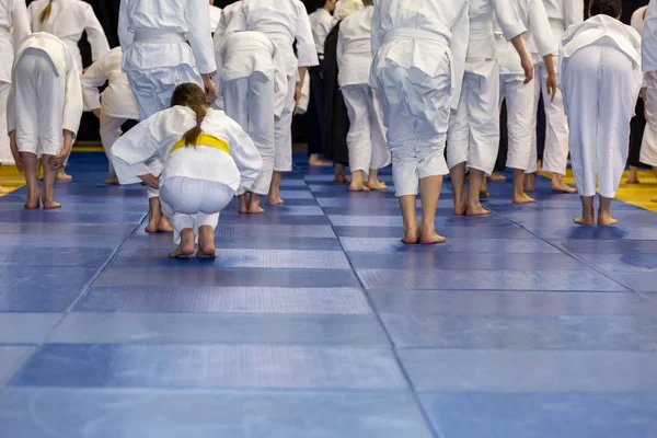 Folk i kimono varmer opp på tatami på kampsportseminar – stockfoto