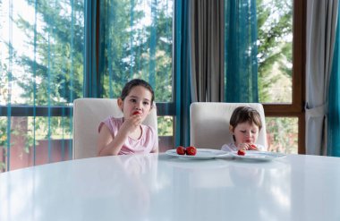 Evde taze olgun çilek yiyen tatlı çocuklar.