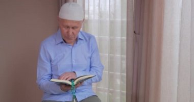 Evde Kuran okuyan yaşlı bir müslüman.