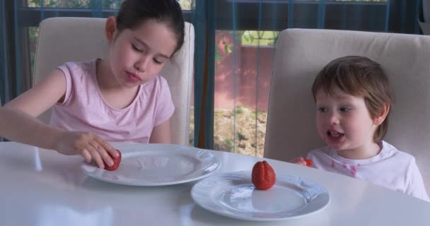 Leuke kinderen die thuis verse rijpe aardbeien eten — Stockvideo