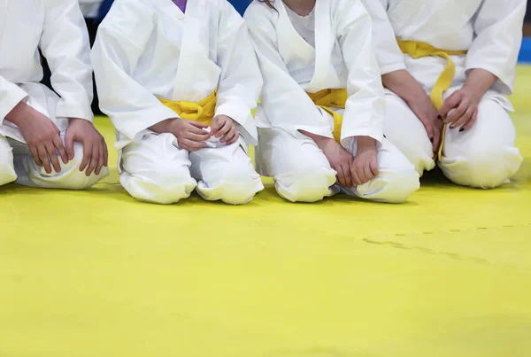 Children in kimono and yellow belts sitting on tatami — Stock Photo, Image