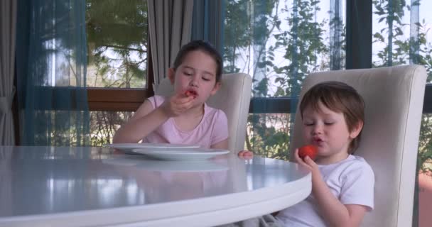 Lindos niños comiendo fresas frescas maduras en casa — Vídeos de Stock