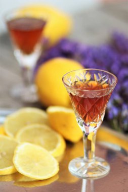 Mor çiçekli limonlu bir bardak konyak.