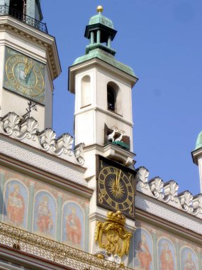 Poznan, Polonya 'da öğle vakti mekanik keçiler, açık mavi gökyüzüne karşı yerel gelenek ve kültürü kutlamak için kasaba kulesinin tepesinde toplanır..