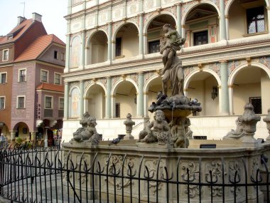 Güneşli bir günde Poznans Eski Pazar Meydanı 'nda fıskiyeler gururla durur. Karmaşık heykellerine ve tarihi cazibesine hayran olan ziyaretçileri cezbeder..