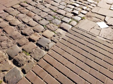 Farklı kaldırım taşları şekilleri görsel bir duvar halısı oluşturur, kırsal kaldırım taşları ile güneşli bir bölgede pürüzsüz modern tasarımlar arasındaki zıtlığı gözler önüne serer..