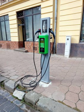 Lviv, Ukrayna - 13 Eylül 2025 Bu elektrikli araba şarj istasyonu hareketli bir şehir caddesinde duruyor, sürücüler için yeşil enerji seçenekleri sunuyor. Asfaltlı kaldırımda kablolar kullanıma hazır..