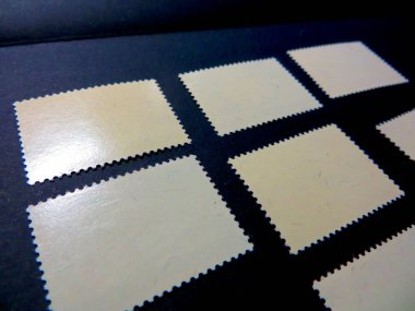 Yakın çekim görüntüsü, bu filatelik koleksiyondaki geçmiş hikayelerini anlatan dokuları ve yüzeyleri gösteren çeşitli eski posta pullarının ters yüzünü ortaya çıkarır..