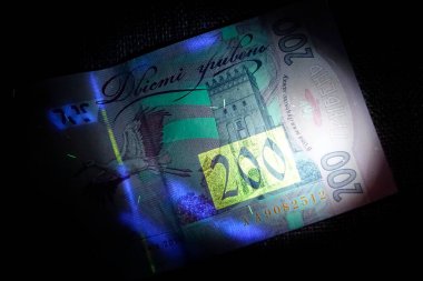 Ultraviyole ışık kullanan Ukrayna hrivnialarının detaylı incelemesi benzersiz güvenlik özellikleri sergiliyor. Bu titiz teftiş para birimlerinin karmaşık tasarımlarını gösteriyor..