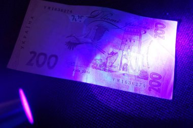 Ultraviyole ışık altında, Ukrayna hrivniaları üzerindeki belirgin desenler ve işaretler canlanıyor, para birimi doğrulaması için hayati önem taşıyan eşsiz güvenlik özellikleri sergiliyorlar.
