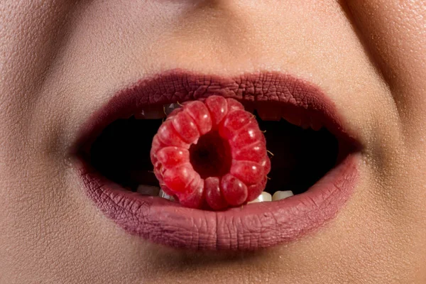 黒い背景にラズベリーを食べる女の子口 — ストック写真