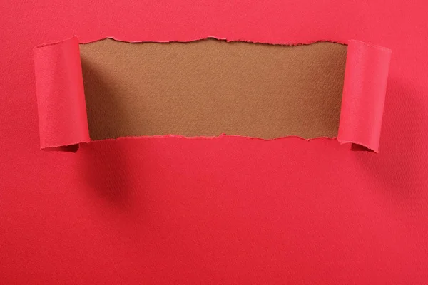Ruban de papier rouge déchiré bord supérieur bouclé révélant fond brun — Photo