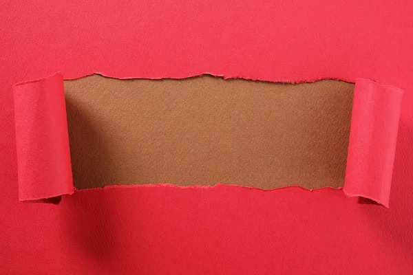 Tira de papel rojo desgarrado rizado borde revelando centro marrón backgrou — Foto de Stock