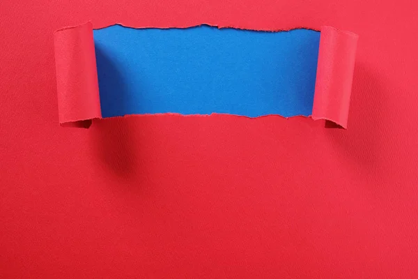 Sönderrivna rött papper strip böjda kant avslöjar top blå bakgrund — Stockfoto