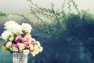 görüntü arka plan ile yaprak yeşil beyaz masada cam vazoda çiçek. sepya vintage sarı tonu
