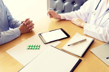Doktor kendine iyi bak, hasta hasta belirtiler ya da evrak bir istişare ile beyaz tablet ekran kırpma pat ile birlikte açıklayan bir erkek doktor dikkatle dinlerken
