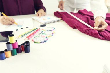  profesyonel moda tasarımcısı çalışma ve çizim ile bilgisayar tablet ve renkli grafikleri tabloda skeçler.