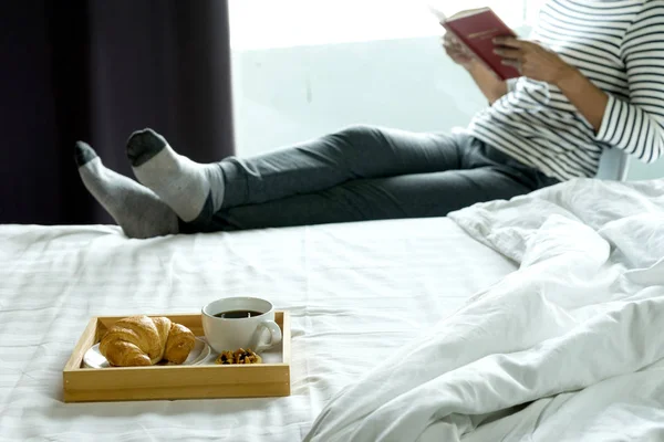 女性が彼女の朝食で幸せな生活の日ベッドに本を読んだをリラックスします — ストック写真