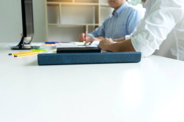 Kadın ve erkek eğitim veya iş için dizüstü bilgisayar ve kağıt işi renk kalemleriyle masada çalışırlar.