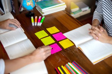 kadın ve adam dizüstü dizüstü bilgisayar ve Kütüphane odadaki kağıt iş renk kalem masada eğitim ya da iş için çalışmak