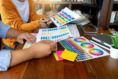 Grafik tasarımı için takım çalışması ahşap masa üzerinde bilgisayar tableti elektronik kalem ve renk grafiği ile çalışıyor