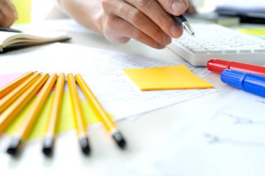 Kadın ve erkek eğitim veya iş için dizüstü bilgisayar ve kağıt işi renk kalemleriyle masada çalışırlar.