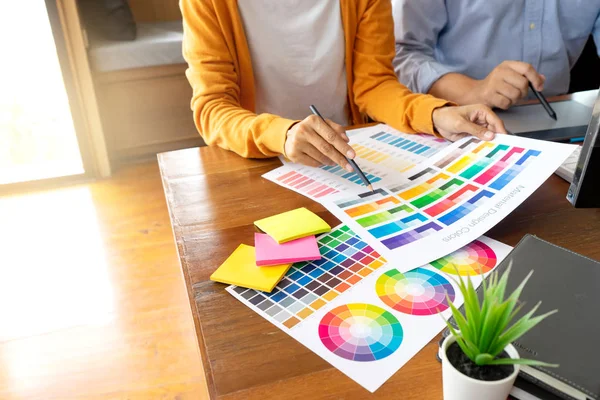 Grafik tasarımı için takım çalışması ahşap masa üzerinde bilgisayar tableti elektronik kalem ve renk grafiği ile çalışıyor