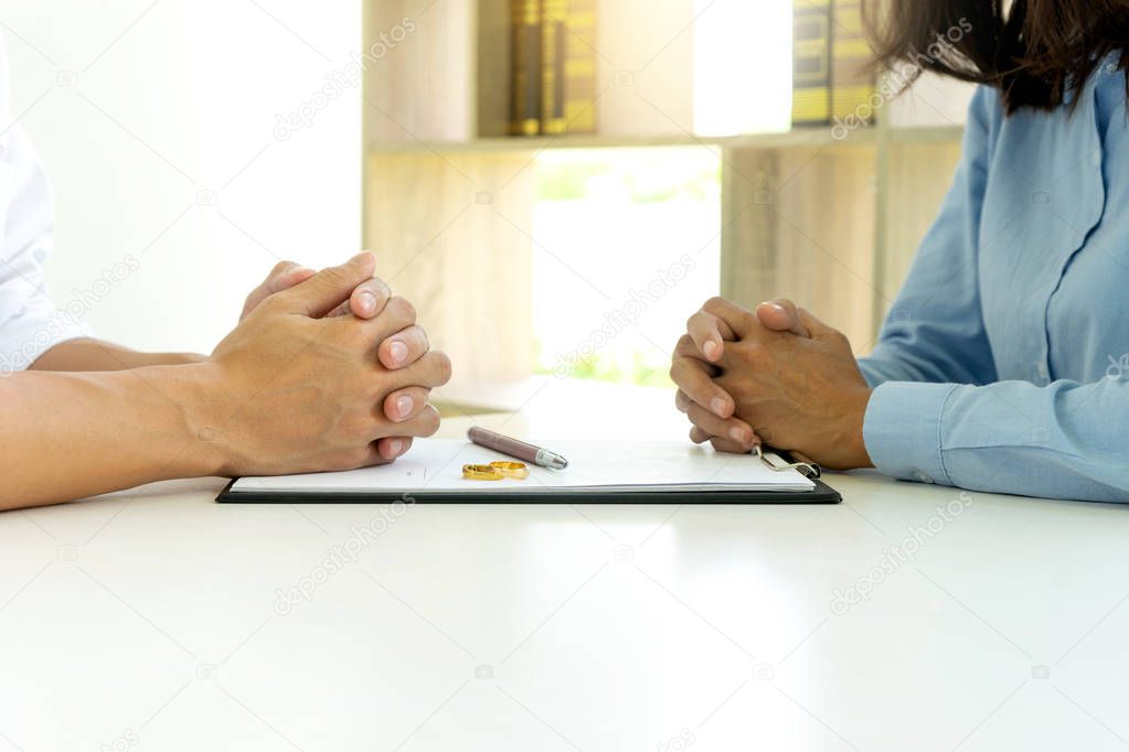 man and woman sit at the table to sign or not on the paper about marry or divorce