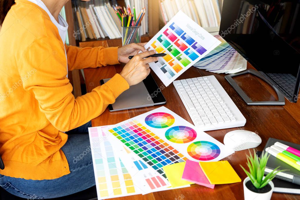 young woman work for graphic design working on wood table with computer tablet electronic pen and color chart
