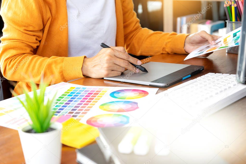 young woman work for graphic design working on wood table with computer tablet electronic pen and color chart