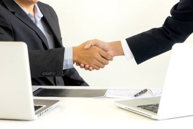 İş adamı ofis masasında bilgisayar bilgisayarı, başarı ya da iş anlaşmaları arasında el sıkışıyor.