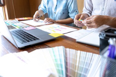 Yeni bir ürün tasarlamak için ofiste çalışan genç tasarımcı grubu, yeni akıllı telefon tasarımı kavramı için renk çizelgesi ve bilgisayar dizüstünü kullanın