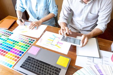 Yeni bir ürün tasarlamak için ofiste çalışan genç tasarımcı grubu, yeni akıllı telefon tasarımı kavramı için renk çizelgesi ve bilgisayar dizüstünü kullanın