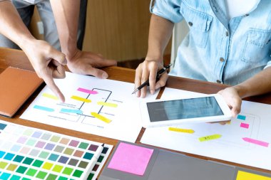 Yeni bir ürün tasarlamak için ofiste çalışan genç tasarımcı grubu, yeni akıllı telefon tasarımı kavramı için renk çizelgesi ve bilgisayar dizüstünü kullanın