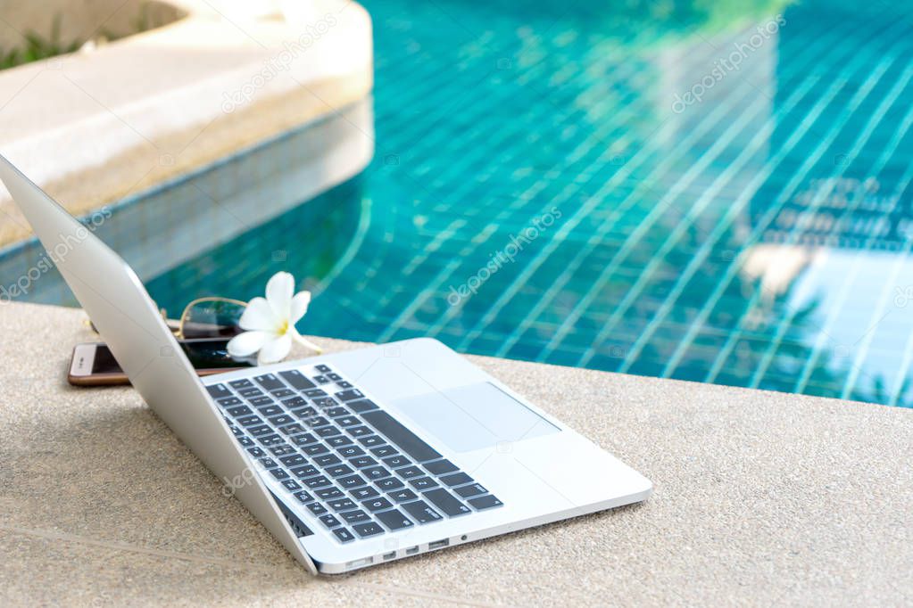 Laptop and smartphone near the swimming pool, modern businessman can work anywhere.