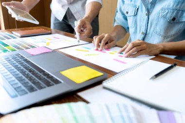 Yeni bir ürün tasarlamak için ofiste çalışan genç tasarımcı grubu, yeni akıllı telefon tasarımı kavramı için renk çizelgesi ve bilgisayar dizüstünü kullanın