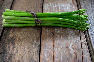 Ahşap arka planda bir grup taze kuşkonmaz, daha fazla fotokopi alanı için çiğ sebze yiyeceği..
