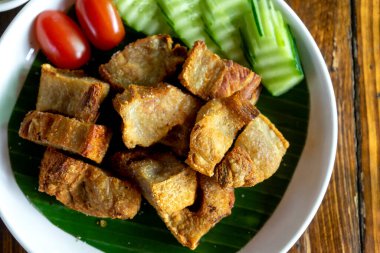 Salatalık ve ahşap bir masada domates tabağında kızartılmış domuz eti.