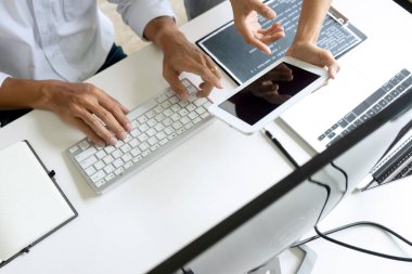 Bilgisayar ekranı önünde çalışan programcı ekibi program kodunu kontrol etmek için tablet kullanın.