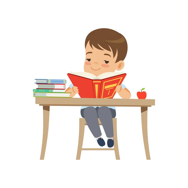 Garçon mignon assis au bureau et lisant un livre, élève de l'école primaire en uniforme vecteur Illustration sur un fond blanc — Image vectorielle