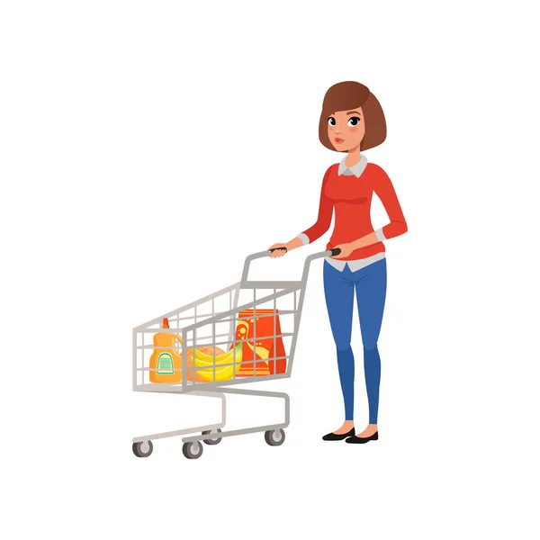 Mujer de dibujos animados de pie cerca del carrito del supermercado con productos. Compras en la tienda de comestibles. Chica joven en blusa y jeans. Diseño de vector plano — Vector de stock