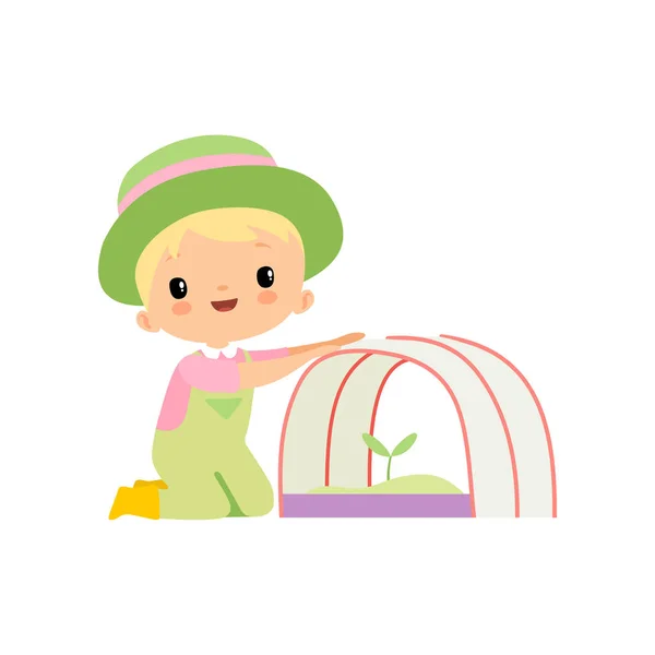 Cute Boy in Overalls, Rubber Boots and Hat Caring for Seedling in Greenhouse, Young Farmer Cartoon Character Engaged in Agricultural Activities Vector Illustration — Stock Vector